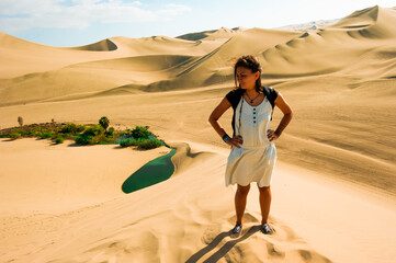 woman crossing The Huacachina Oasis, in the desert sand dunes near the city of Ica, Peru