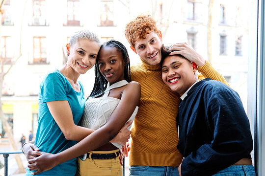 Multiethnic gay and lesbian couple embracing together on a balcony