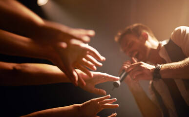 Hands, fans at concert and musician at music festival with microphone on stage with front row...