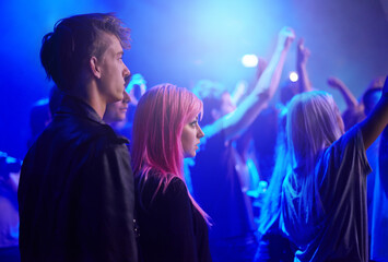 Couple in crowd, man and woman at music festival, neon lights and watching live band performance on...