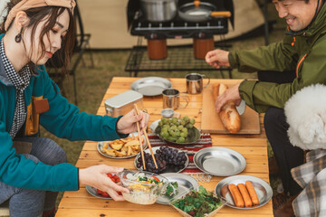 秋冬のキャンプ場で料理・キャンプ飯を作る女性キャンパーと仲間(アジア人)
