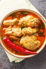 Chicken cooked in spicy gravy made with authentic flavour of malvani closeup on the bowl on the table. Vertical top view from above