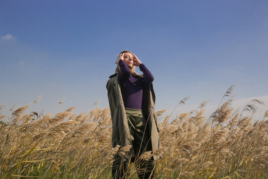 Serie of photos of female model in purple turtleneck and green trousers posing on meadow. Outdoor fashion portrait with natural light.