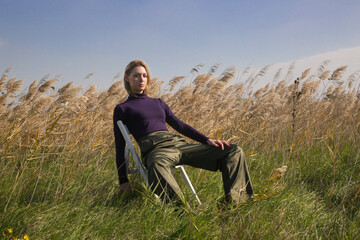 Fototapeta na wymiar Serie of photos of female model in purple turtleneck and green trousers posing on meadow. Outdoor fashion portrait with natural light.