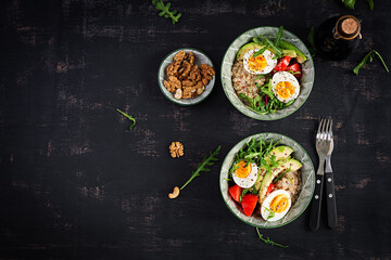 Breakfast oatmeal porridge with boiled eggs, avocado, tomatoes and green herbs. Healthy balanced food. Top view, flat lay