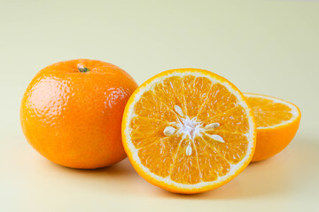 Fresh cut oranges and oranges isolated on soft yellow background