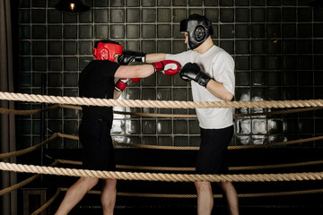 Two big guys boxing and sparring in the ring in head guard helmets and gloves.