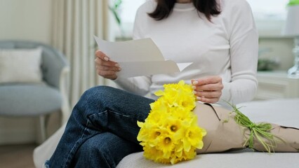 Close-up of bouquet of yellow flowers, woman's hands holding congratulatory note