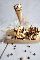 
Vanilla chocolate ice cream cone. On a white wooden background. Sweets