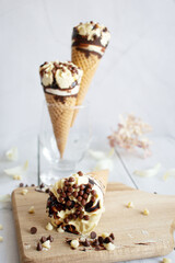 
Vanilla chocolate ice cream cone. On a white wooden background. Sweets