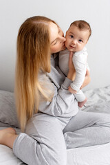 Fototapeta na wymiar Mom and baby play on the bed. Mother and son, happy family, beautiful blonde girl and cute baby at home.