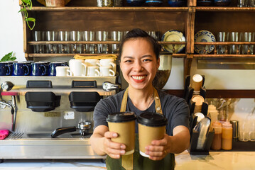 Vietnamese smiling waitress holding paper cups with coffee in a cafe