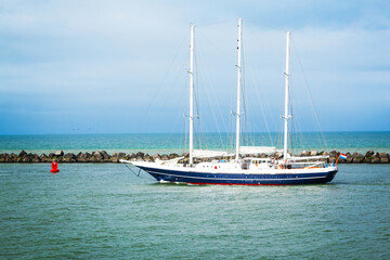 Naklejka na ściany i meble Sailing three masted yacht sailing in the bay near the breakwater.