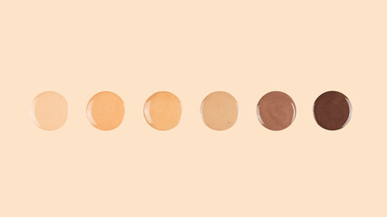 Diverse skin tone makeup foundation drops on beige background.