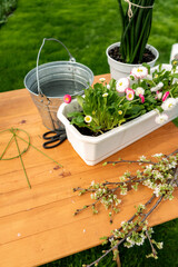 flower plants in white pots on wooden table and garden tools