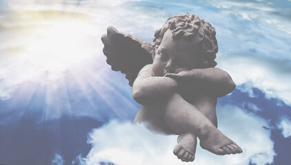 An angel sleeps in the clouds in the sky. Fragment of an ancient statue.  Horizontal image.