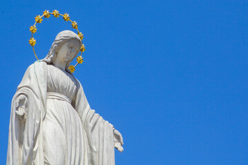 Fototapeta premium Virgin Mary is Queen of heaven. Antique statue against blue sky. Copy space.