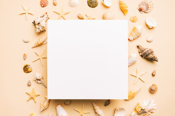 Summer time concept with blank greeting card and blank white paper on colored background. Seashells from ocean shore in the shape of frame separated with space for text top view