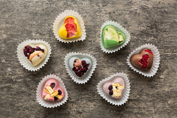 chocolate sweets in the form of a heart with fruits and nuts on a colored background. top view with space for text, holiday concept