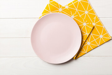 Top view on colored background empty round pink plate on tablecloth for food. Empty dish on napkin with space for your design