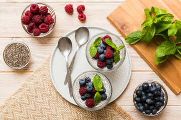 Healthy breakfast or morning with chia seeds vanilla pudding raspberry and blueberry berries on table background, vegetarian food, diet and health concept. Chia pudding with raspberry and blueberry
