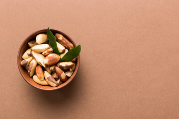 Fresh healthy Brazil nuts in bowl on colored table background. Top view Healthy eating bertholletia concept. Super foods