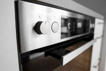 Knobs of electric oven in modern kitchen, closeup