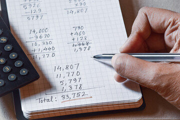 Handwritten calculation of monthly expenses on notebook with calculator. - obrazy, fototapety, plakaty