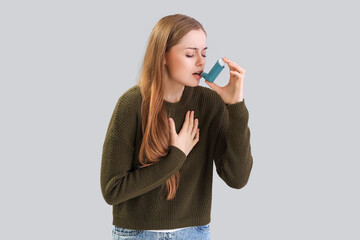Young woman with inhaler on  grey background