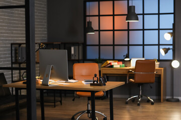 Interior of dark office with accountant's workplace and glowing lamps