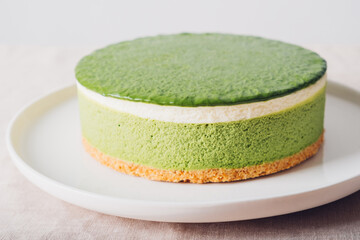 Layered ice cream  matcha cheesecake on white plate. Gluten free no bake dessert, close up. Healthy sweet food.