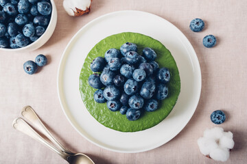 Ice cream matcha cheesecake with fresh blueberries, top view. Gluten free no bake dessert, flat lay style. Healthy sweet food.