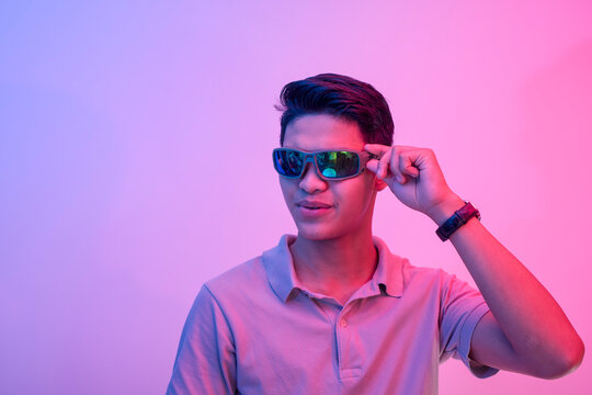 A cocky and brash young asian man wearing shades feeling handsome and cool. Party vibe with blue and red colors.