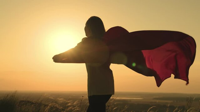 girl superhero sunset. man superhero red cape in the wind at dawn. red cape superhero concept. children's play in the park outdoors in the sun. fancy dress. halloween. festive outfit. reincarnation