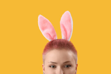 Young woman with bunny ears on yellow background, closeup