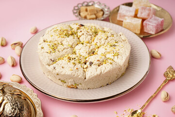 Plate of tasty Tahini halva with pistachios on pink background
