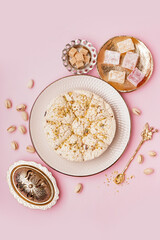 Plate of tasty Tahini halva with pistachios and turkish delight on pink background