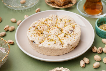Plate of tasty Tahini halva with pistachios on green background