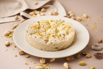 Plate of tasty Tahini halva with pistachios on beige background