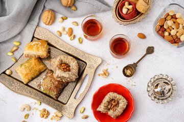 Tray with tasty baklava and glasses of Turkish tea on light background