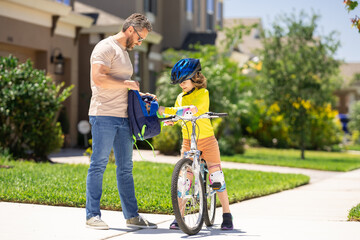 Father and son riding bike on a park. Child in safety helmet with father riding bike on summer day....