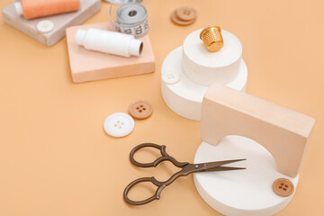 Podiums with tailor's supplies on beige background, closeup