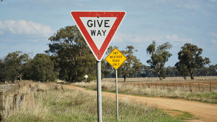 A Give-way and Dry Weather Road Only sign in Rural Victoria Australia.