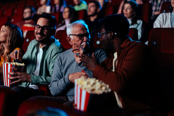 Man gesturing be quiet in movie theater.