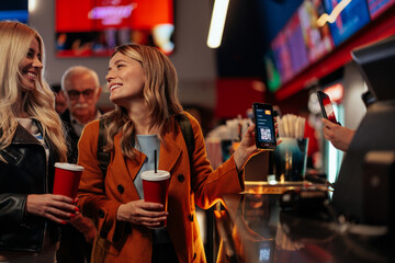 Woman paying with mobile app in the cinema.