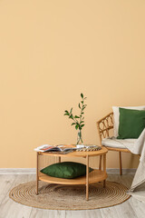 Armchair and coffee table with vase and magazines near beige wall