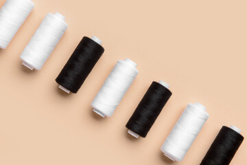 Black and white thread spools on color background