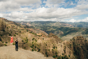 Obraz premium Young female tourist enjoying the view into Waimea Canyon, Kauai, Hawaii