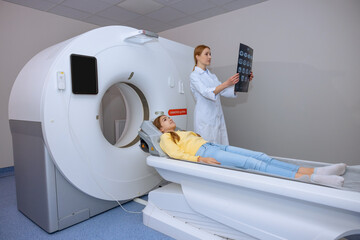 Young adult blonde female doctor checking mri picture in clinic.