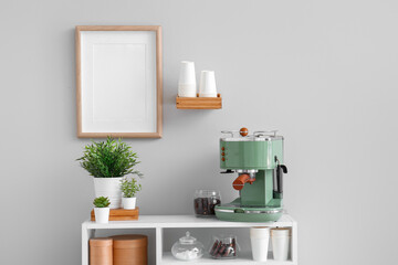 Modern coffee machine, jar with beans and houseplants on table near white wall
